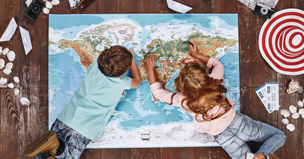 two kids looking at a map of the world on the floor