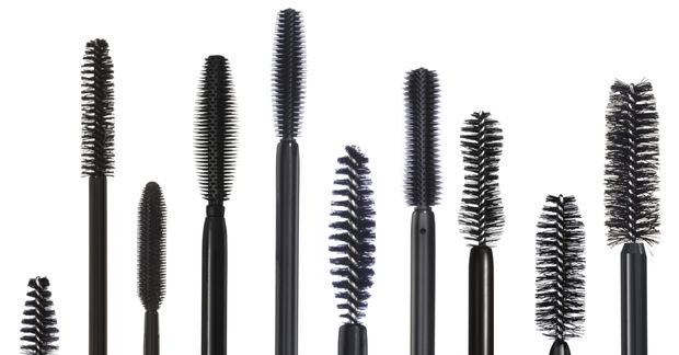 A row of various mascara wand brushes in different shapes and sizes displayed against a white background.