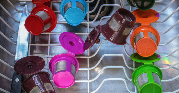 Colorful reusable coffee pods in various colors drying on a dishwasher rack, viewed from above.