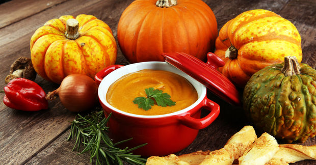 Pumpkin soup in red pot with autumn vegetables.