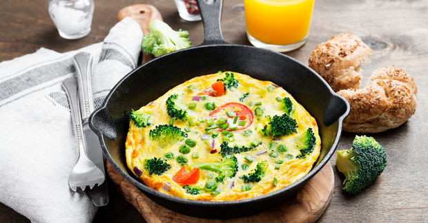 Vegetable frittata in cast iron skillet with bread.