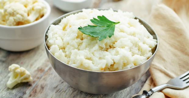 Mashed cauliflower in bowl garnished with fresh parsley.
