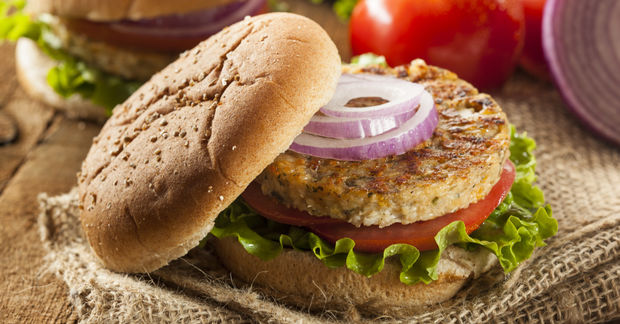 Veggie burger with vegetables on whole grain bun.