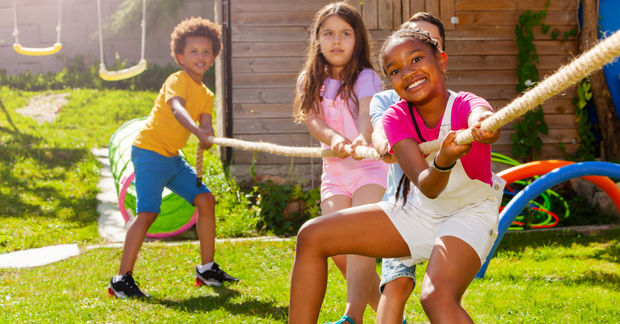 photo Three children playing tug-of-war in backyard.