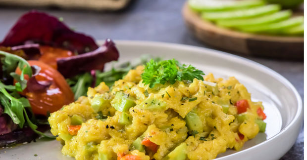 Plate of turmeric-spiced scrambled eggs with peppers and herbs, served with beetroot and green vegetable salad.