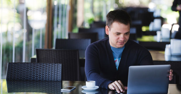 Concentrated Concentrated male student studying with a laptop and drinking espresso.