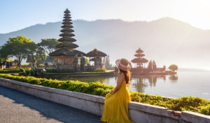 A female tourist relaxing and enjoying a beautiful view of a temple in Bali.