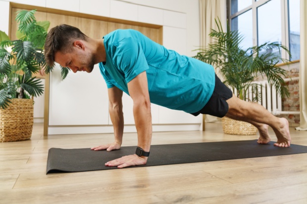 A young man maintains a plank position.