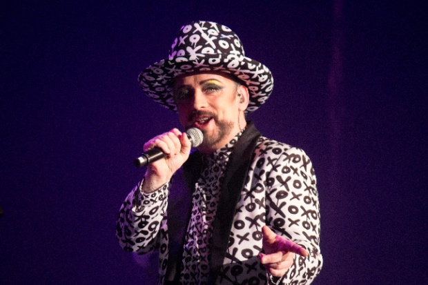 Boy George holding a microphone.
